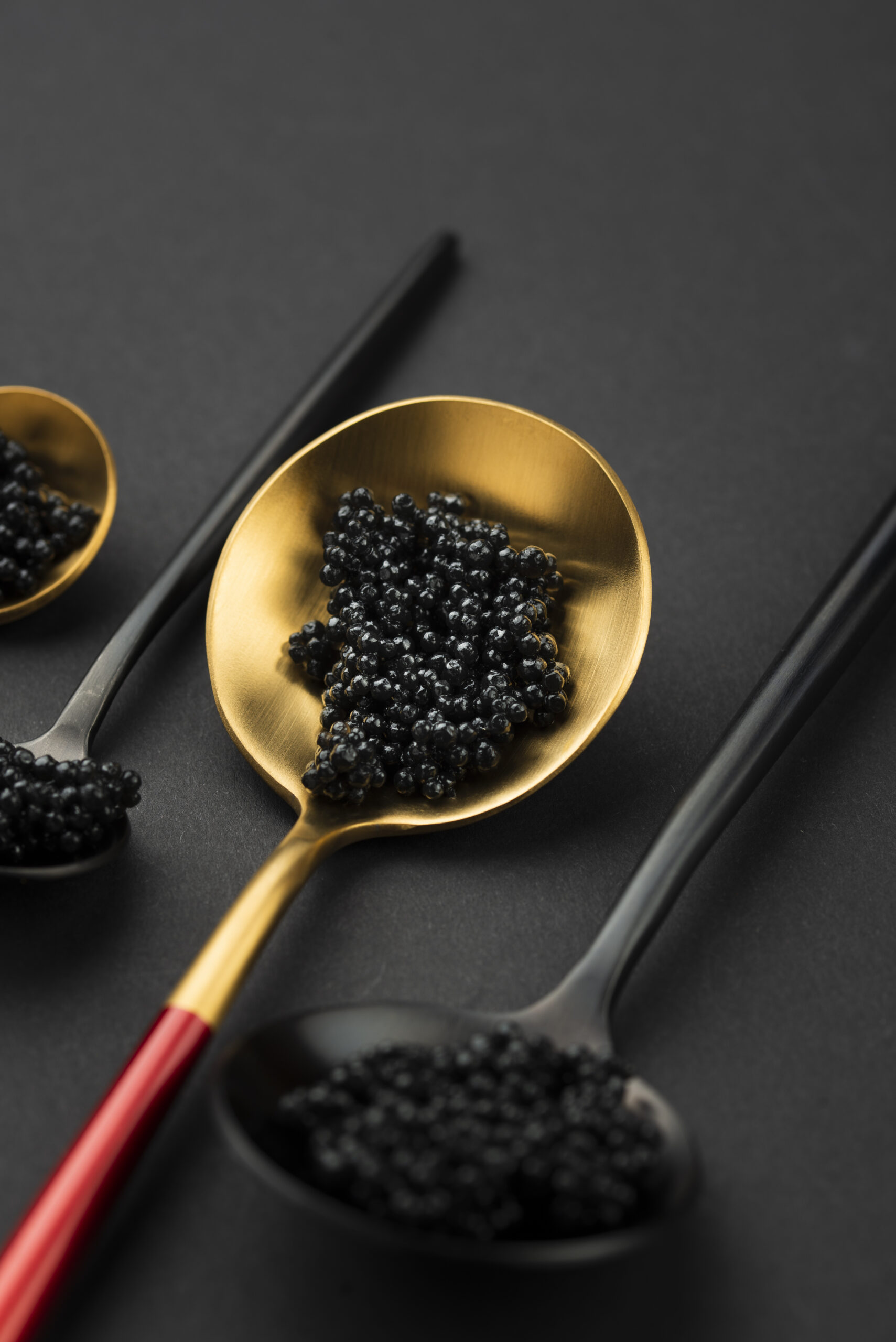 Două linguri cu caviar negru — una aurie, una mată